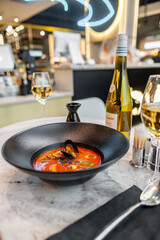 Tom yam in a black plate on a table in a restaurant