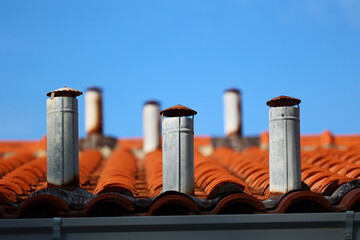 Komin na czerwonym dachu budynków widok na miasto.  - obrazy, fototapety, plakaty