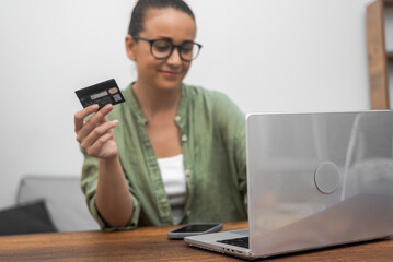A woman in eyeglasses effortlessly handles online payments and shopping using her credit card and...