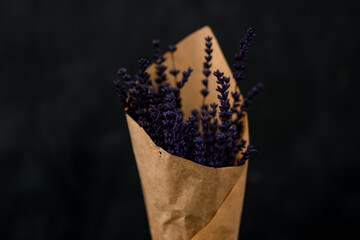 Close up view of delicate fragnant lavender flowers bouquet wrapped in paper on dark background