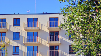 A modern residential building in the vicinity of trees. Ecology and green living in city, urban environment concept. Modern apartment building and green trees. Ecological housing architecture. 