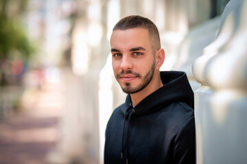 A portrait of a stylish young man standing in a city street and smiling