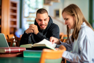 Young man supporting visaully impaired woman to study in library