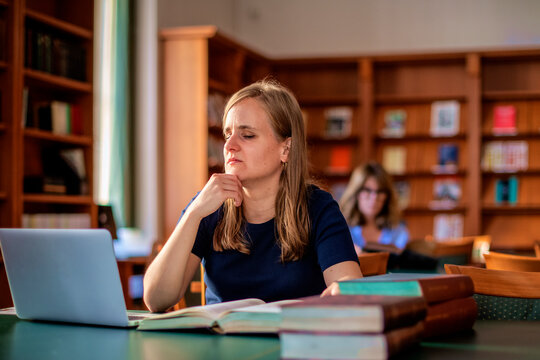 A visually impaired young woman sitting and studying in the university library