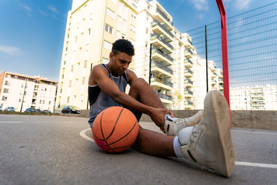 young black man holding on to a sprained ankle during a game, a sports injury