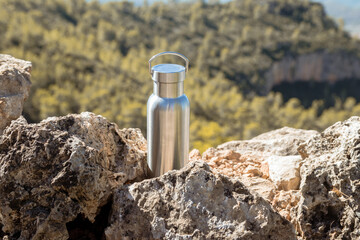 Thermal bottle on a rock on top of a mountain