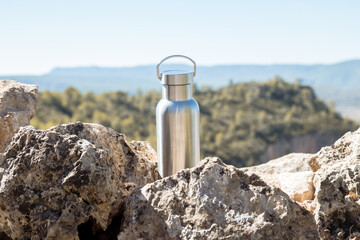 Thermal bottle on a rock on top of a mountain