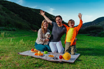 Happy family with dog on a picnic in the mountains - 652049690