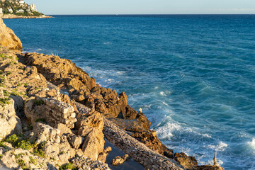 View of the rocky coast and blue waves of the Mediterranean Sea.
