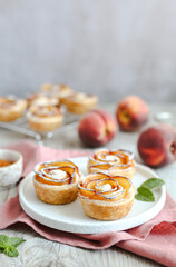 Nectarine Roses made of puff pastry, on a white plate. Buttery, flaky and crispy puff pastry rolls with layers of flavorful nectarine slices. Pink napkin.
