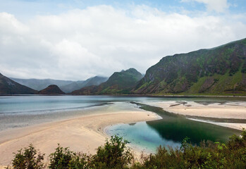 Lofoten fjords and lakes cloudy landscape with sandy beach, lough, and mountains (Norway). Summer...