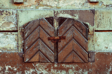 Old vintage small window with closed antique wooden shutters.