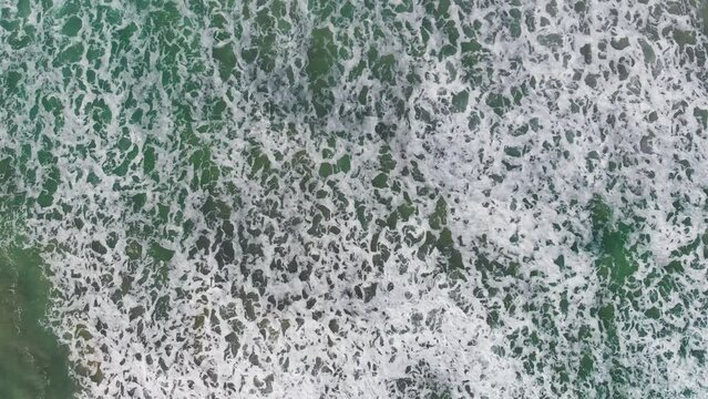 Beautiful waves along the shoreline, overhead aerial view from drone