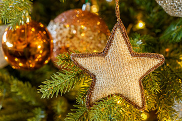 selective focus on a burlap star ornament on a decorated holiday tree in warm neutral tones