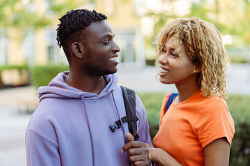 Smiling African American young couple in love, man and woman, friends talking on the street