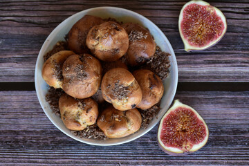 Delicious homemade profiteroles cakes with cocoa cream filling and chocolate chips on plate, fig halves on wooden table background. Top view.