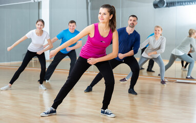 Cheerful young woman enjoying active dances in modern dance studio.