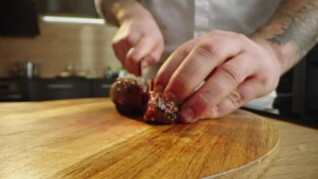Close-up view of seared duck slicing by the professional cook on wooden cutting board in the kitchen