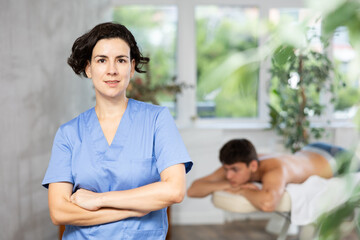 Portrait of friendly female masseur with an inviting visit to the spa salon