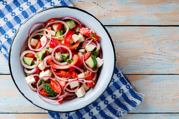 Fresh Salad Bowl with Tomatoes, Cucumbers, Onions and Feta Cheese on Wooden Table. Top view. Copy space
