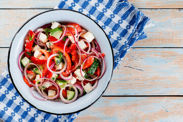Fresh Salad Bowl with Tomatoes, Cucumbers, Onions and Feta Cheese on Wooden Table. Top view. Copy space