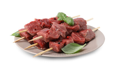 Wooden skewers with cut fresh beef meat, basil leaves and spices isolated on white