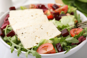 Bowl of tasty salad with tofu and vegetables on table, closeup