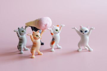Cute toy kittens hold an ice cream cone in their paws. Pink background. Baby food. Photo