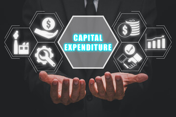 Capital expenditure concept, Businessman hand holding capital expenditure icon on virtual screen. - obrazy, fototapety, plakaty
