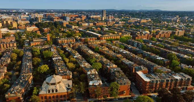 View of sunlit facades of old multistoried buildings of Boston, Massachusetts, USA. Cityscape full of greenery from aerial view.