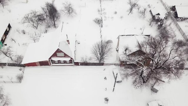 Aerial view of colorful wooden old houses along road in winter village. Flying over countryside, snowstorm snowfall blizzard overcast cold frozen weather. Country lifestyle rural suburban concept 4k 3