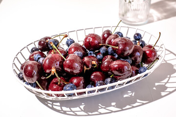 Mixed blue berry and cherry in th white wire basket.