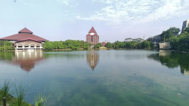 Depok, Indonesia - June 29, 2023: View of the Kenanga lake with the background of an University of Indonesia building at Depok, Indonesia. Clear blue sky.