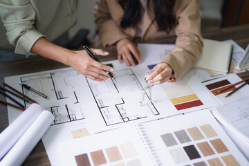 Two female architects discuss interior design building project and use divider compass on blueprint - 652113635