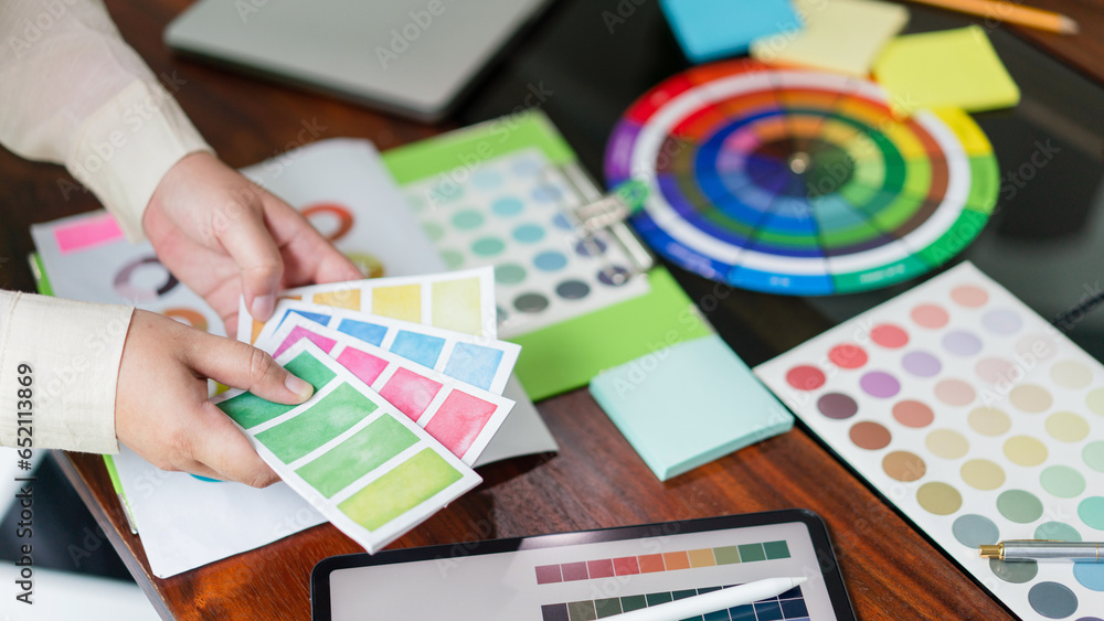 Poster creative graphic designer holding color swatch to comparing color on tablet for designing project