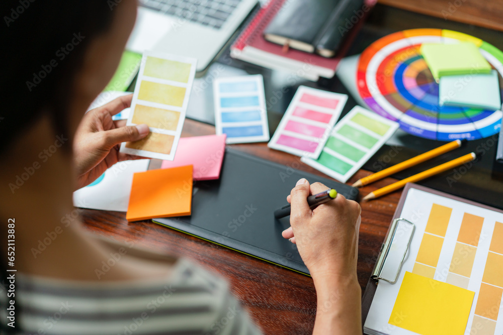 Poster creative graphic designer holding color swatch to choosing color and working to designing on tablet
