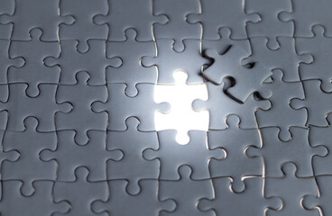 Solving the puzzle of success Illuminating concepts in Business. White jigsaw puzzle with missed and shining piece. Solution concept. Connecting the glowing solution concept for business success.