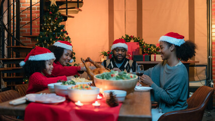 African family of parents and children Having fun on the dinner table in the evening in a Christmas decorated house.