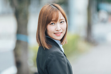 振り返って微笑むスーツの女性　Business