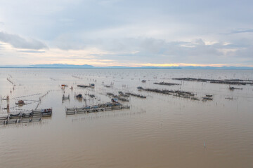 Aerial view of fishing trap net in canel with fisherman urban city village town houses, lake or river. Nature landscape fisheries and fishing tools at Pak Pha, Songkhla, Thailand. Aquaculture farming
