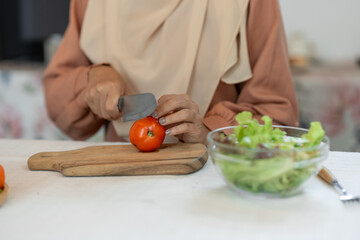 healthy food, weight loss concept Beautiful Asian Muslim woman Attractive woman wearing headscarf prepares delicious food at kitchen chopping tomatoes to nourish skin useful fruit and vegetable ideas