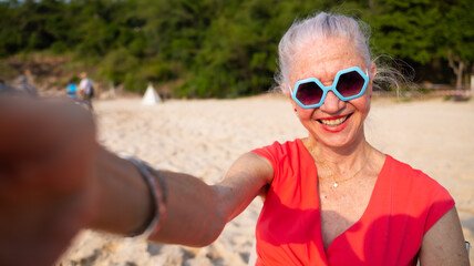 Selfie. Elderly caucasian female taking selfie with smartphone on beach. Vacation trip summer...