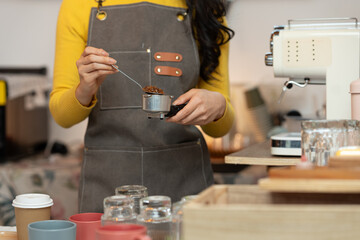 Owner, Asian woman holding coffee powder while grinding to prepare coffee in a cafe Baristas use coffee machines to make coffee for customers. Freelance Startup Business Idea or SME