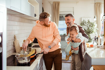 Gay male couple and their adopted son preparing lunch together at home