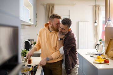 Young male gay couple preparing lunch and cooking together at home