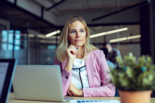 Middle Aged Blonde Caucasian Woman Working And Using A Laptop In A Modern Business Office