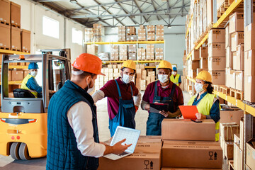 Diverse group of warehouse workers wearing covid19 or coronavirus masks working in a warehouse