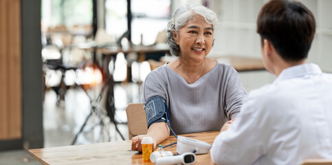 Asian elderly female patient Being Reassured By Doctor In Hospital Room