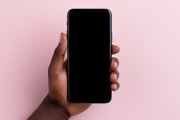 Hand holding smartphone with a black blank screen isolated on a pink background