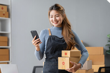 Female entrepreneur using mobile phone and preparing orders for shipping in a warehouse.